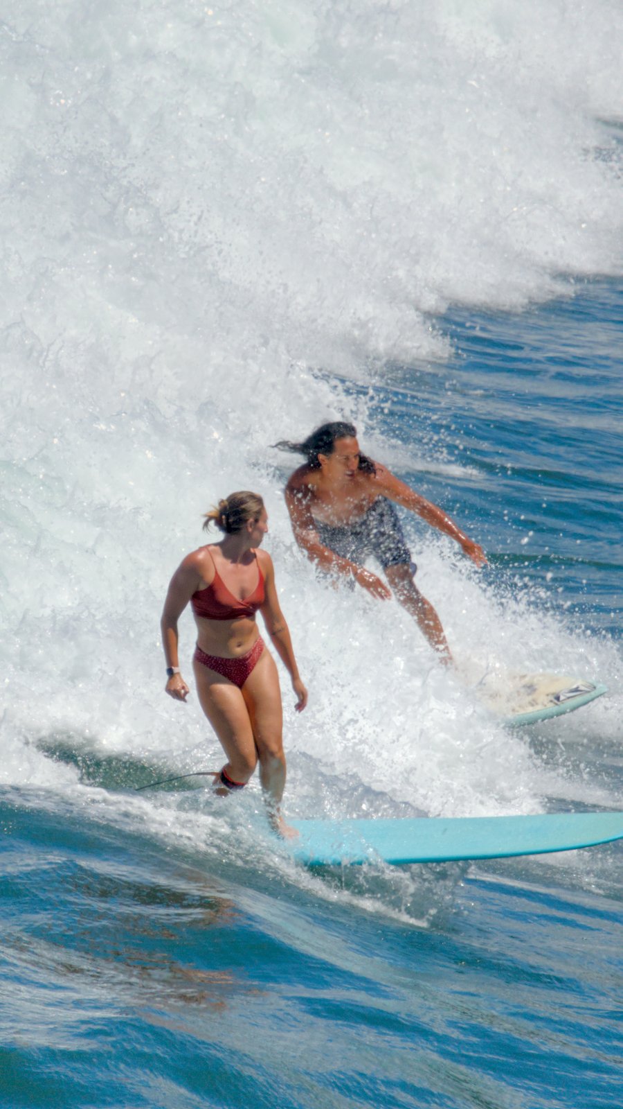 Woman surfing at Honolii looking at nearby surfer